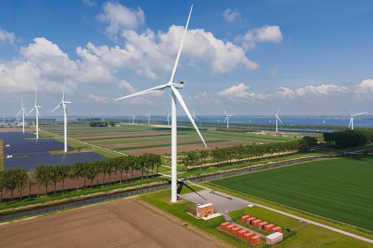 Windkraft- und PV-Anlagen auf einer Freifläche, davor ein Batteriespeicher