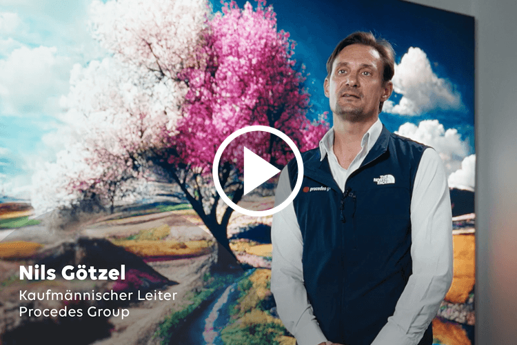 Mann mit weißem Hemd und dunkelblauer Weste steht vor einem großen Bild mit blühendem Baum und blauem Himmel