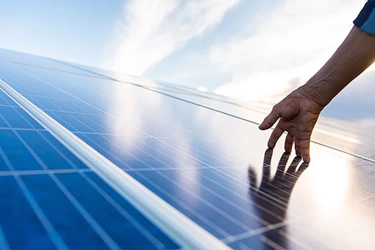 Ein Hand streicht über sonnenbeschienene PV-Module