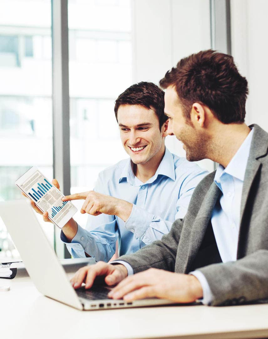 Zwei Männer an einem Arbeitsplatz mit einem Laptop, die ein Diagramm ansehen
