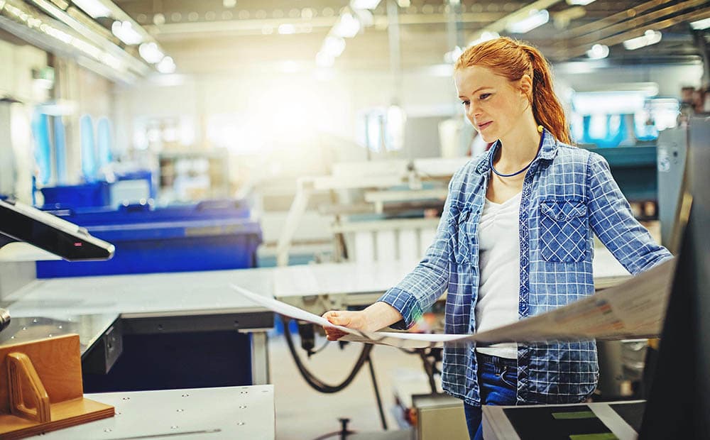 Eine junge Frau, die einen Proof in einer Druckerei prüft