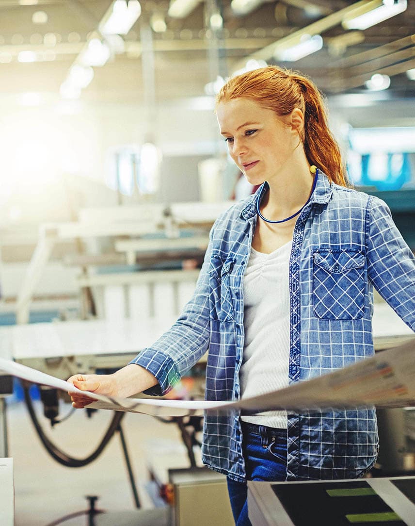 Eine junge Frau, die einen Proof in einer Druckerei prüft