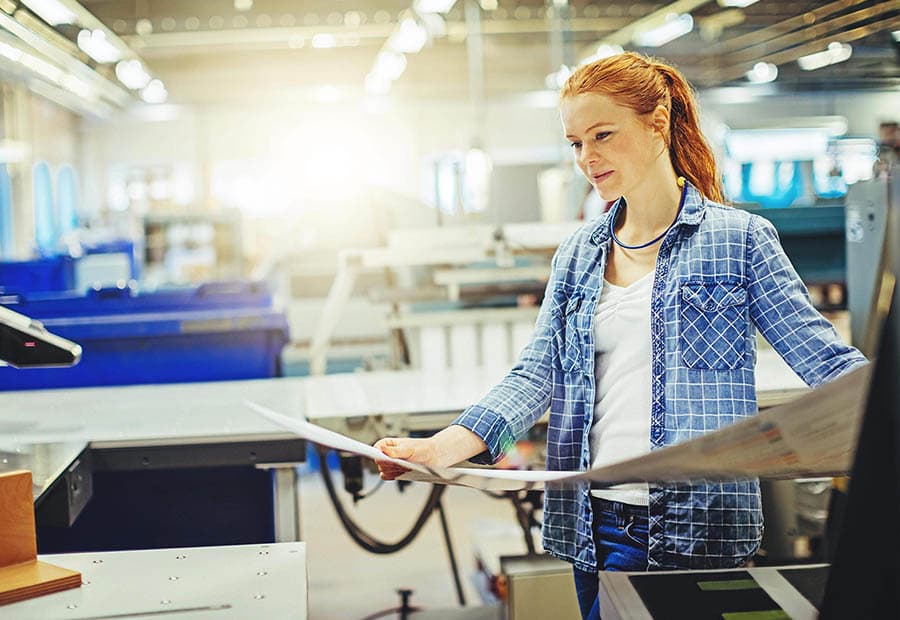 Eine junge Frau, die einen Proof in einer Druckerei prüft