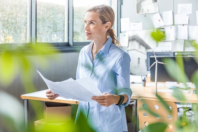 Eine Frau in einem hellen Büro hält einen Plan in den Händen.