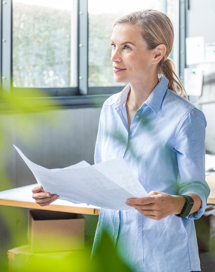 Eine Frau in einem hellen Büro hält einen Plan in den Händen.