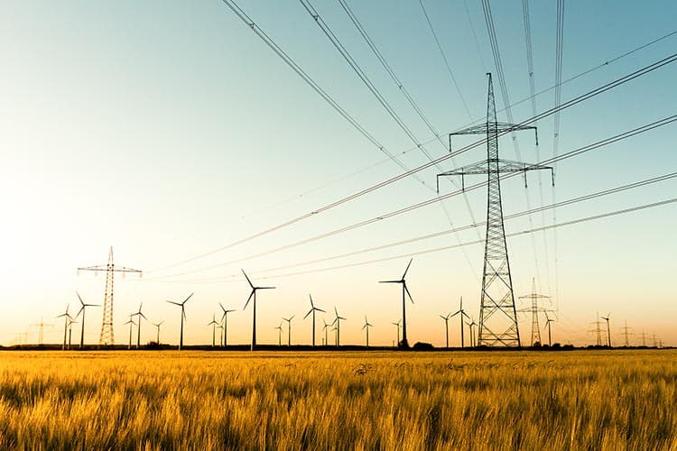 Ein weites Feld mit Strommasten und Windkrafträdern