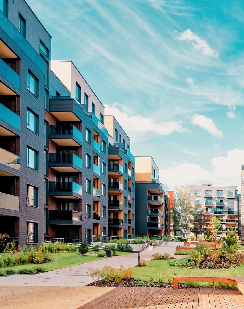 Moderne Wohnblöcke in warm-brauner Tönung, davor Grün- und Aufenthaltsflächen