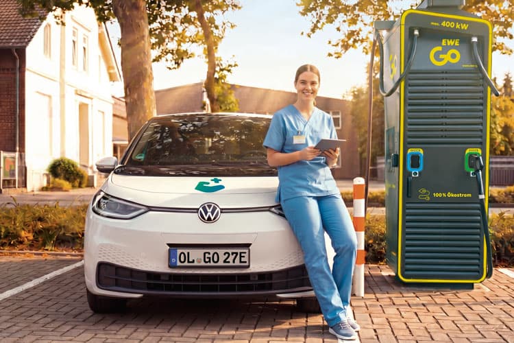 Eine Frau lädt ihr Pflegedienst-Fahrzeug an einer EWE Go Ladesäule