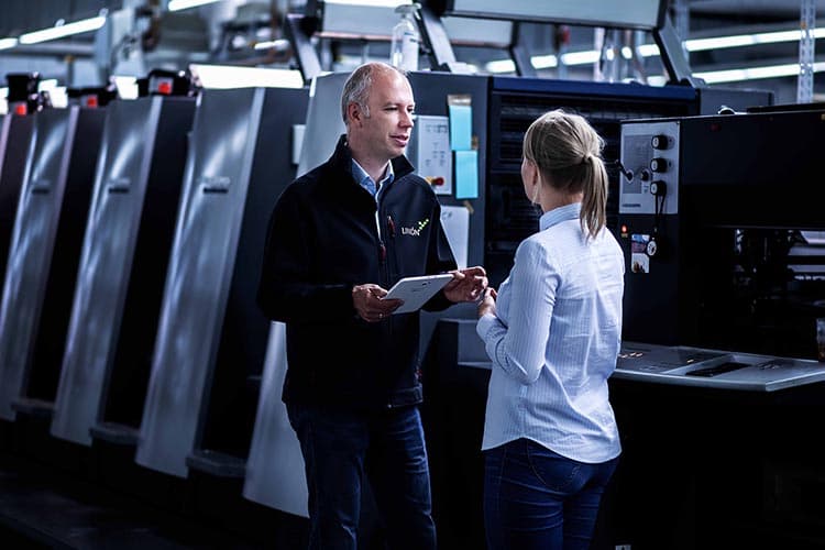 Ein Mitarbeiter von Limon mit einem Tablet in der Hand bespricht etwas mit einer Mitarbeiterin in einer Produktionshalle.