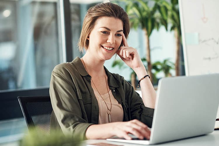 Eine Frau guckt auf ein Notebook und hört interessiert zu.