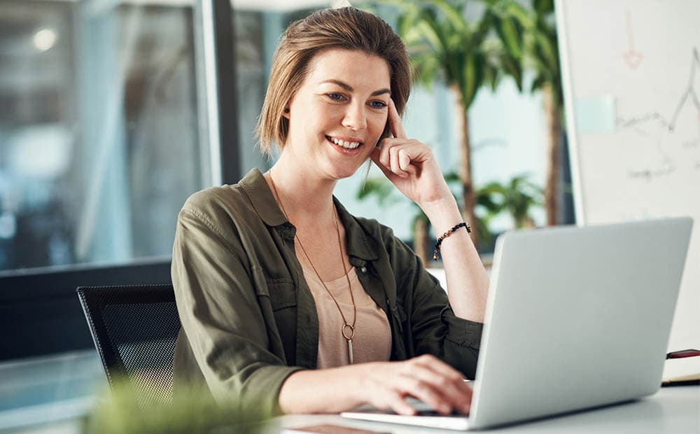 Eine Frau guckt auf ein Notebook und hört interessiert zu.