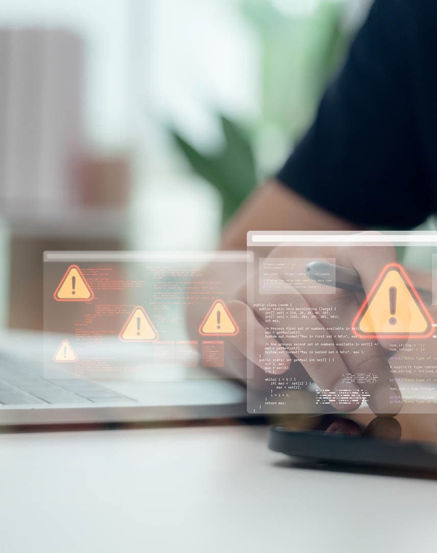 Eine Person benutzt ein Smartphone auf einem Schreibtisch mit Laptop, darüber "schweben" kleine Screens mit Warnhinweisen.