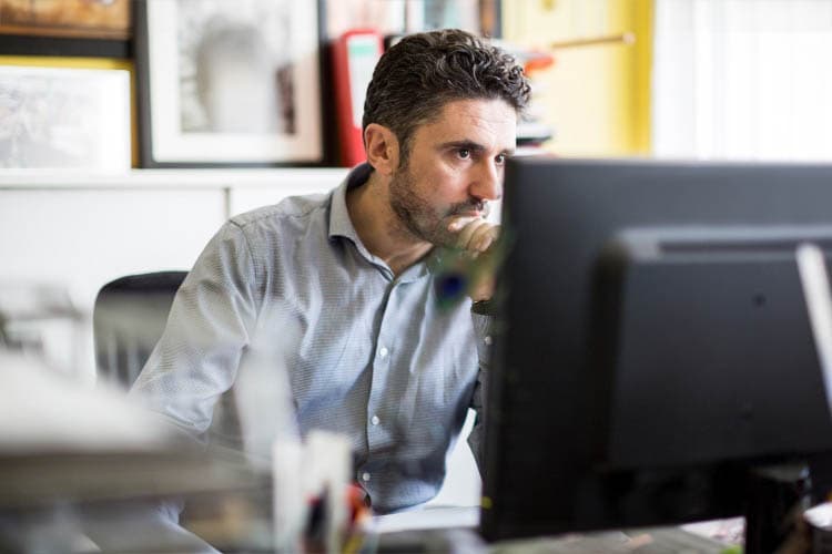 Mann schaut interessiert auf Computer-Bildschirm