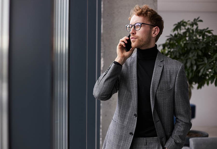 Ein Mann im Anzug steht in einem Büro und telefoniert.
