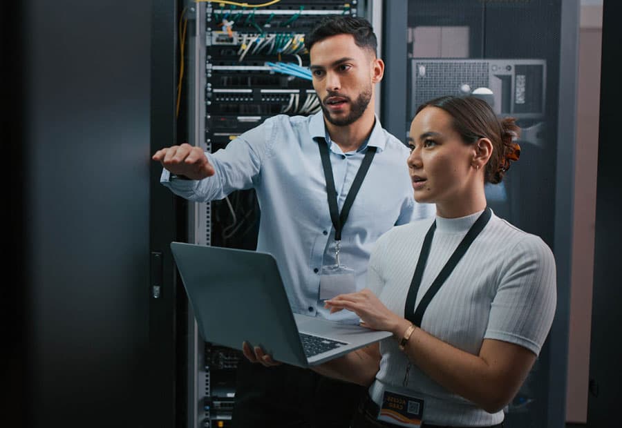 Eine Frau und ein Mann arbeiten mit einem Laptop in einem Serverraum