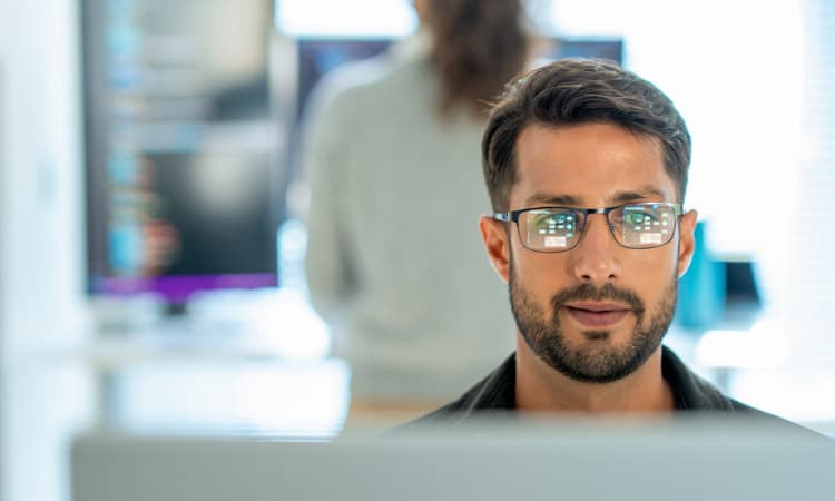 Ein Mann mit Brille, der auf einen Bildschirm schaut