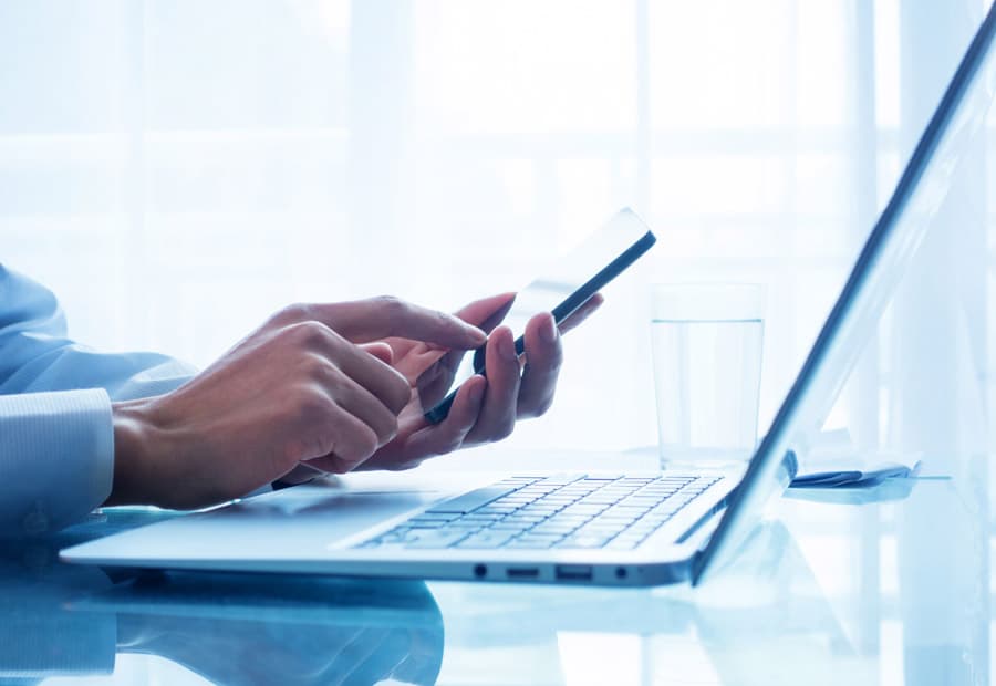Ein Notebook und ein Smartphone, das von einer Person benutzt wird