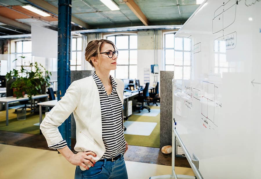 Frau betrachtet ein Whiteboard in einem Büro