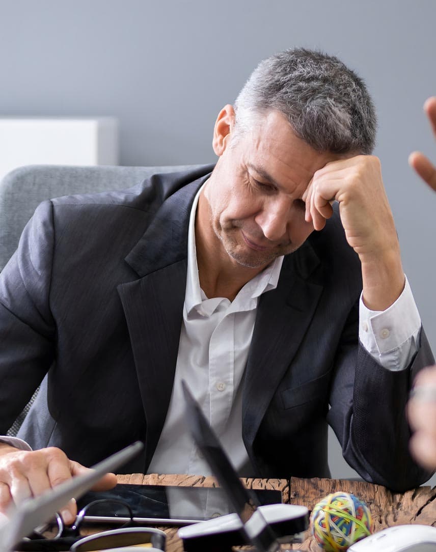 Nachdenklicher Geschäftsmann an einem Besprechungstisch zwischen argumentierenden Kollegen