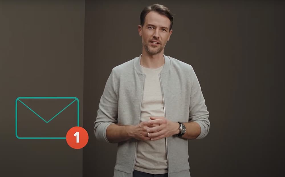 Ein Video-Moderator guckt in die Kamera und führt dabei die Hände zusammen.