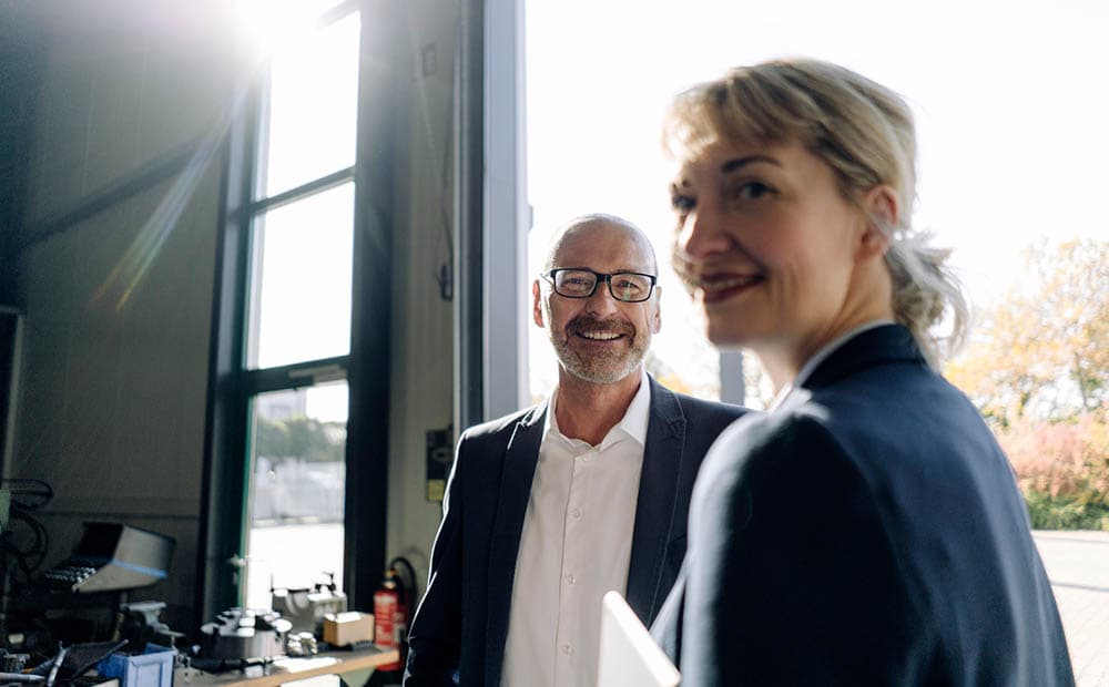 Frau und Mann im Business-Look lächeln in die Kamera