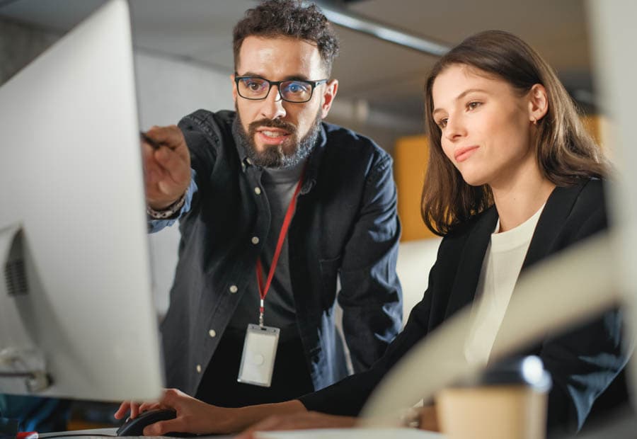Eine Frau und ein Mann arbeiten an etwas auf einem Computerbildschirm.