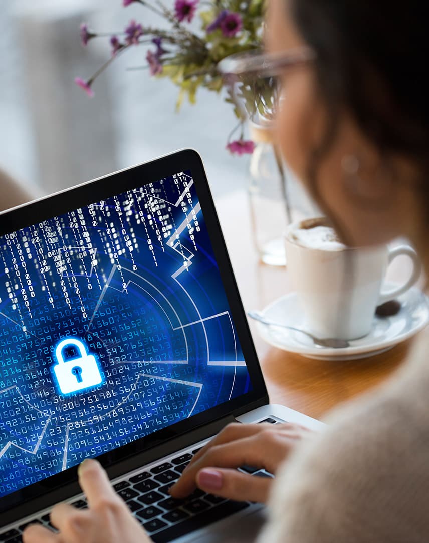 Eine Frau versucht, ein Notebook zu entsperren, auf dem Code zu erkennen ist, im Hintergrund eine Kaffeetasse