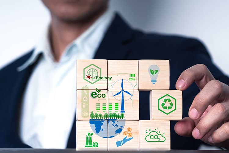 Ein Mann mit Sakko sortiert mit seiner linken Hand Holzwürfel, die verschiedene Dekarbonisierungsmaßnahmen für Unternehmen darstellen