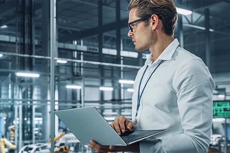 Ein Ingenieur mit Laptop in einer Produktionshalle