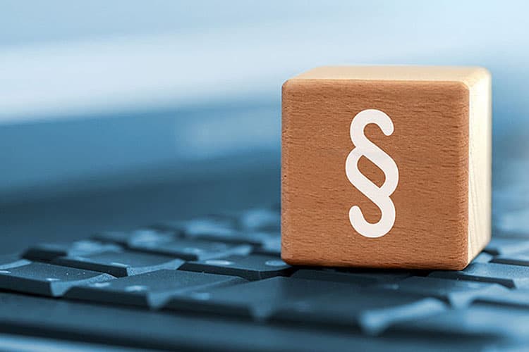 Ein Paragraphen-Zeichen auf einem Holzwürfel, der auf einer Tastatur steht