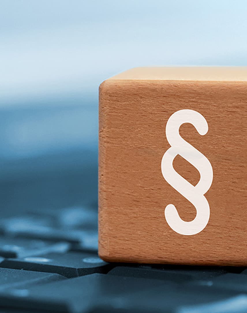 Ein Paragraphen-Zeichen auf einem Holzwürfel, der auf einer Tastatur steht