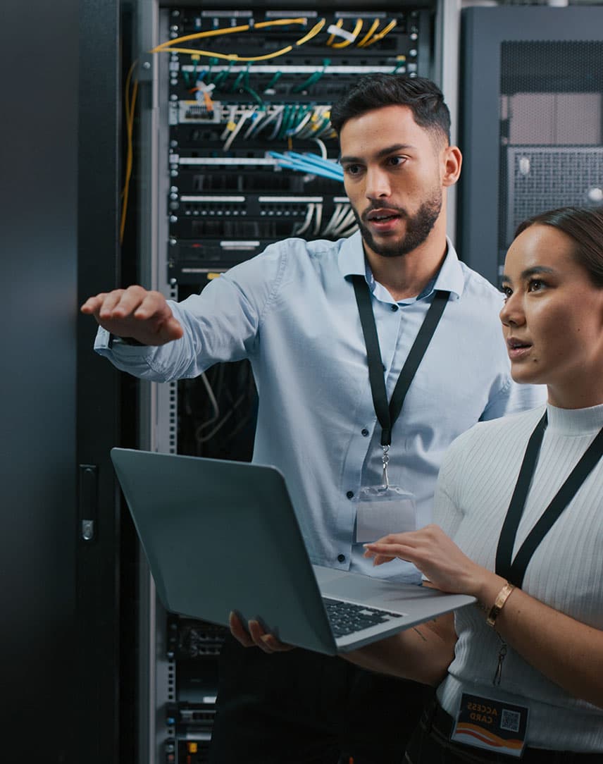 Ein Mann und eine Frau mit Laptop, die in einem Serverraum etwas überprüfen