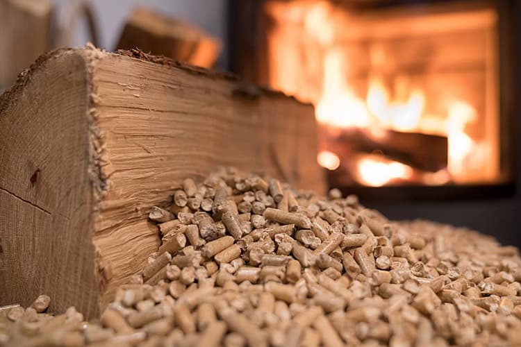 Ein Scheit Holz und Pellets vor einem Kaminofen
