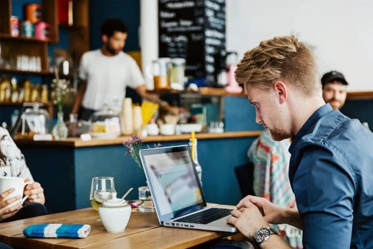 Ein junger Mann arbeitet an seinem Laptop im Cafe