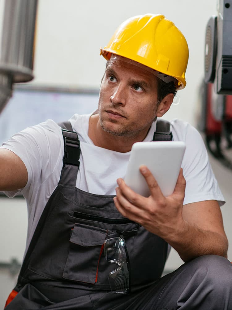 Ein Handwerker mit Tablet, der eine Leitung überprüft