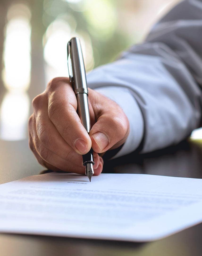 Die Hand eines Manns, der etwas mit Füller auf ein Dokument schreibt