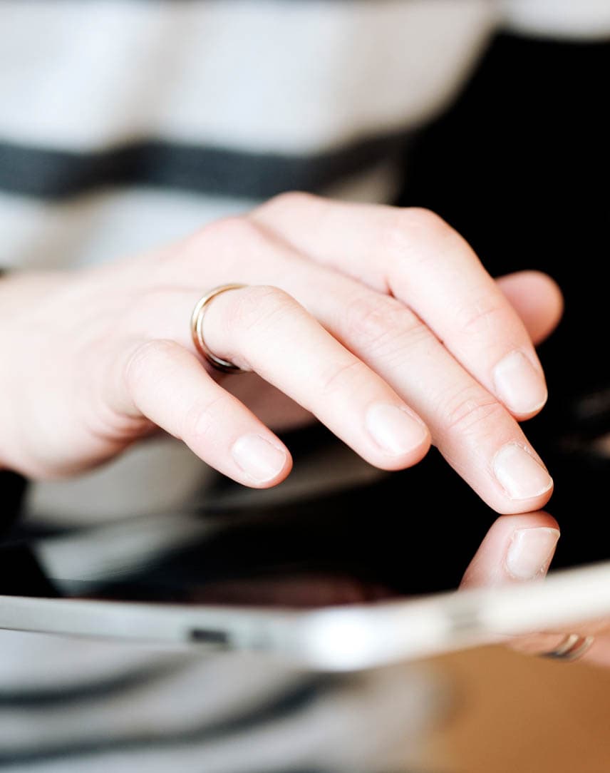 Die Hände einer weiblichen Person, die auf einem Tablet scrollt