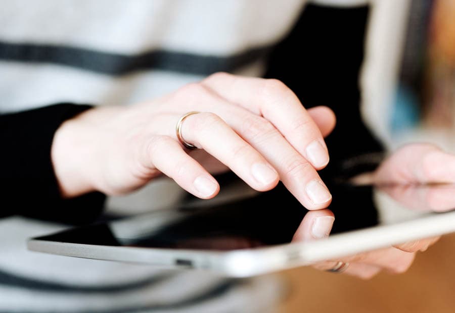 Die Hände einer weiblichen Person, die auf einem Tablet scrollt