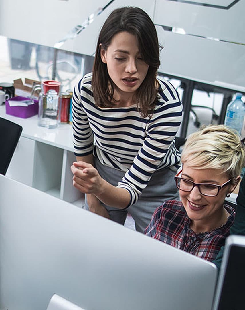 Mehrere Menschen im Büro schauen gemeinsam auf Computerbildschirme