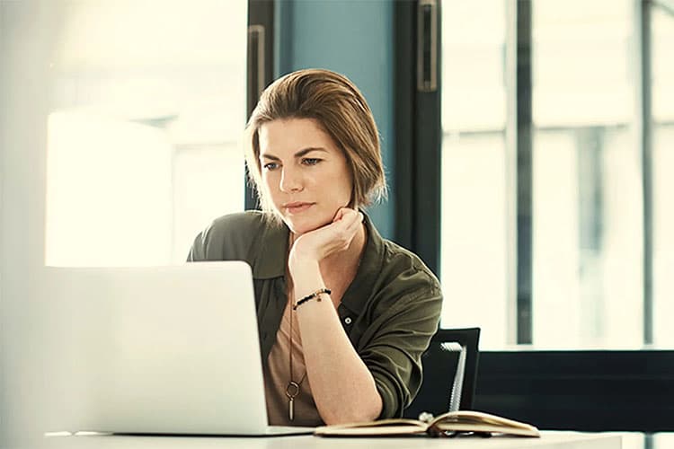 Frau schaut zufrieden auf Laptop
