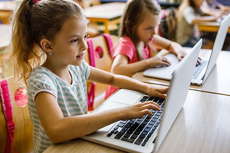 Grundschülerinnen an ihren Laptops.