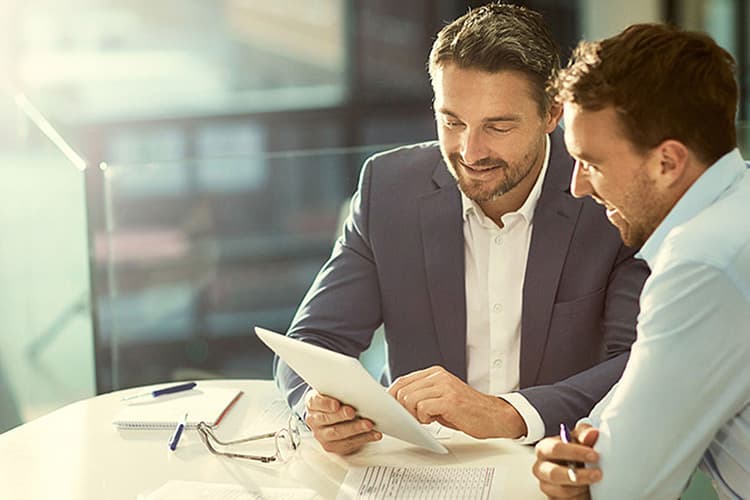 Zwei Männer im Business-Look schauen auf ein Handy