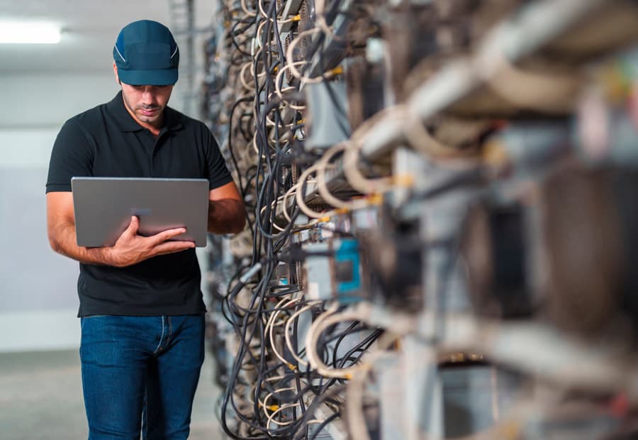 Ein Mann mit Notebook an Server-Racks