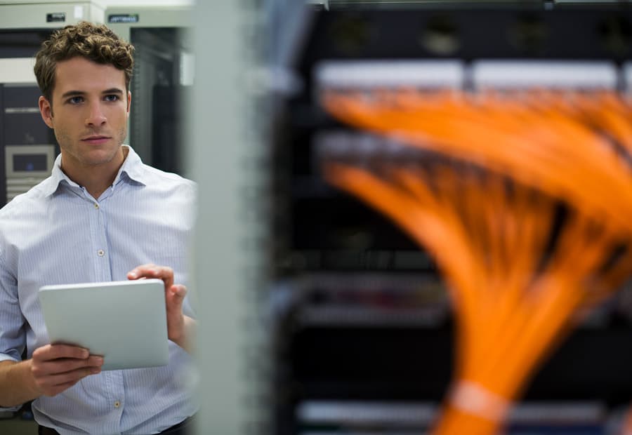 Ein Mann mit Tablet, der auf ein Server-Rack guckt