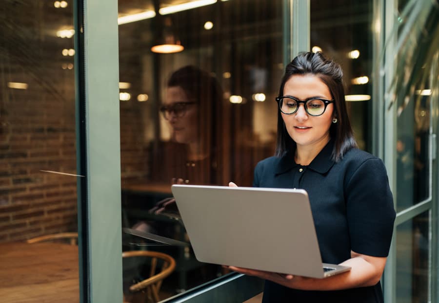 Eine Frau, die stehend auf ein Laptop guckt