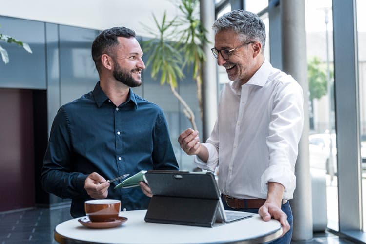 Zwei Männer unterhalten sich an einem Stehtisch in einem Unternehmen.