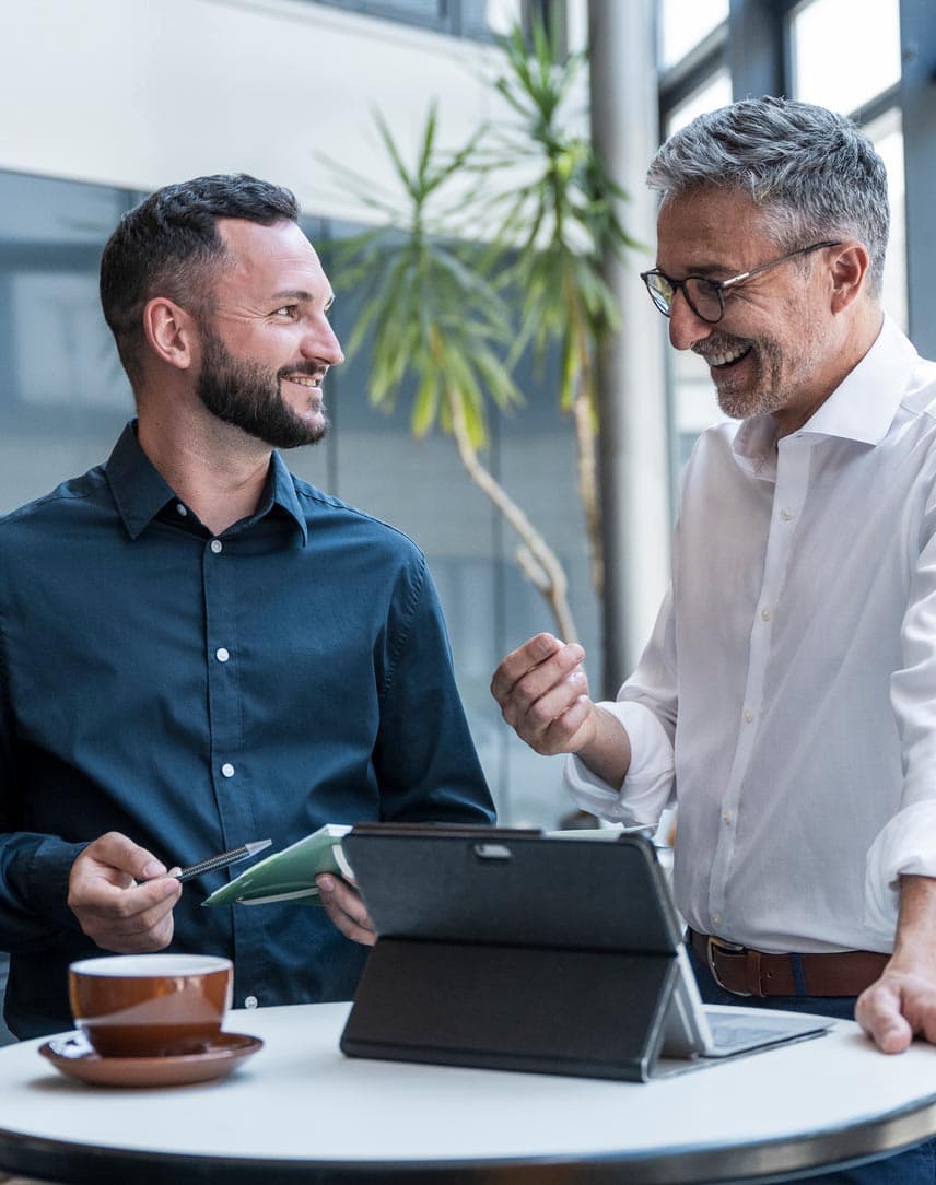 Zwei Männer unterhalten sich an einem Stehtisch in einem Unternehmen.
