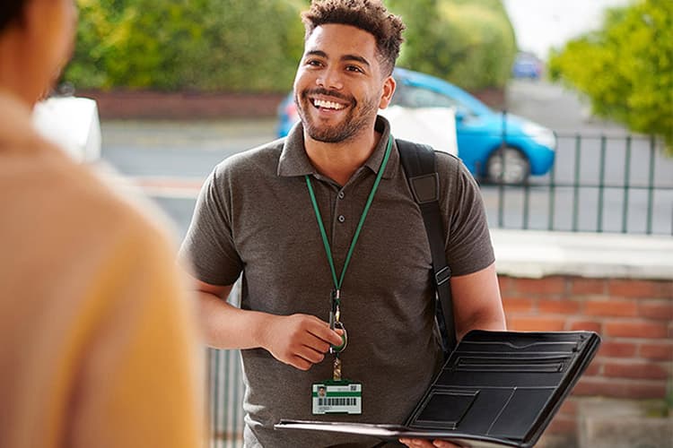 Freundlicher Mann an der Haustür mit Beratungsmappe in der Hand