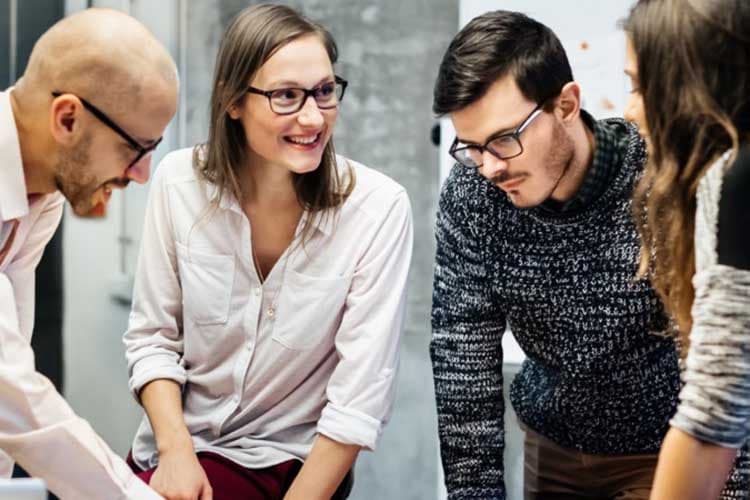 Junge Leute, die sich bei der Arbeit angeregt über ein Thema unterhalten.