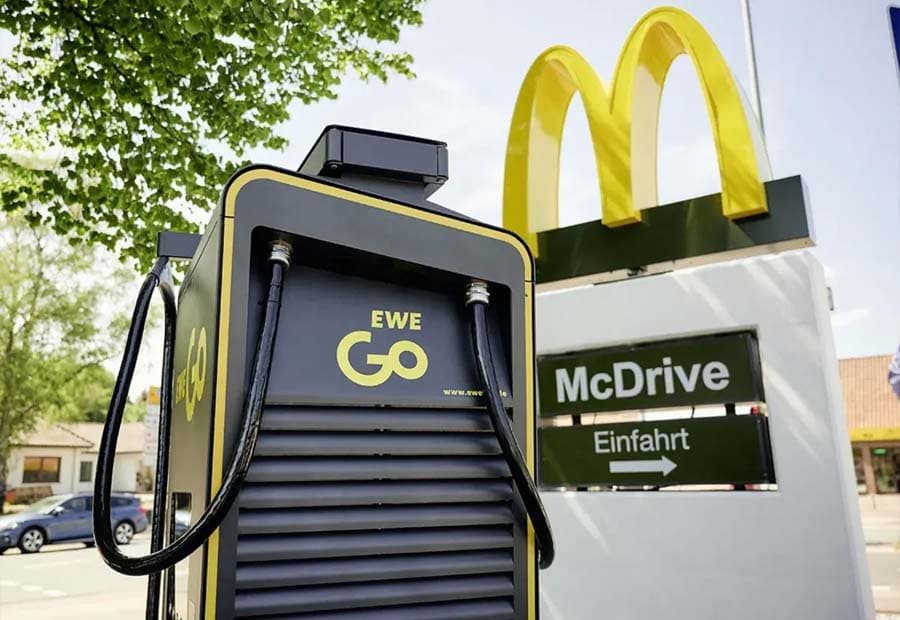 Eine EWE Go-Ladesäule neben einem Mc-Donalds-Zeichen auf einer McDrive-Säule